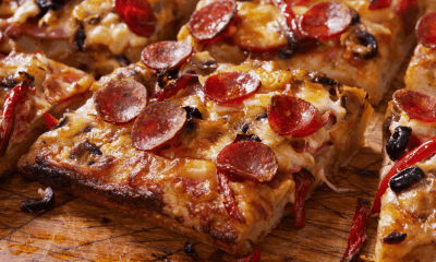 Detroit Style Pizza Recipe: A Taste of Detroit Pan Pizza 26 Close-up of a crispy Detroit-style pizza slice, highlighting the thick crust, caramelized cheese edges, and a delicious combination of toppings including pepperoni, black olives, and red bell peppers.