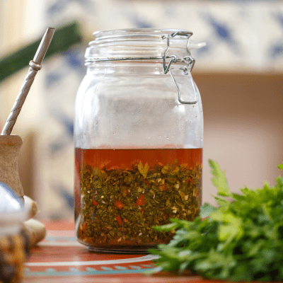 Chimichurri Sauce: Learn How to Make the Authentic Chimichurri Sauce Recipe from Argentina 32 Close-up of freshly made chimichurri sauce in a glass jar, showcasing its vibrant green color and texture.