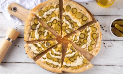 Dill-icious Pickle Pie Pizza Recipe: A Twist on Classic Dill Pickle Pie! 190 Pickle Pie Pizza Sliced dill pickle pizza on a wooden board with a golden crust and creamy garlic drizzle.